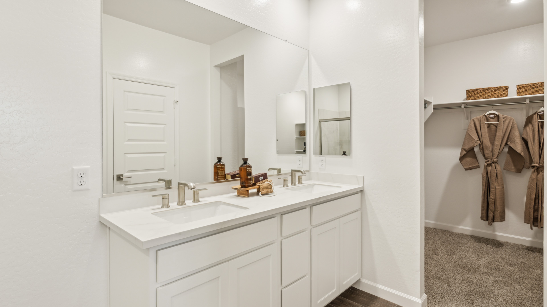 Modern primary bathroom with double vanities, quartz countertops with a walk-in shower and a walk-in closet.