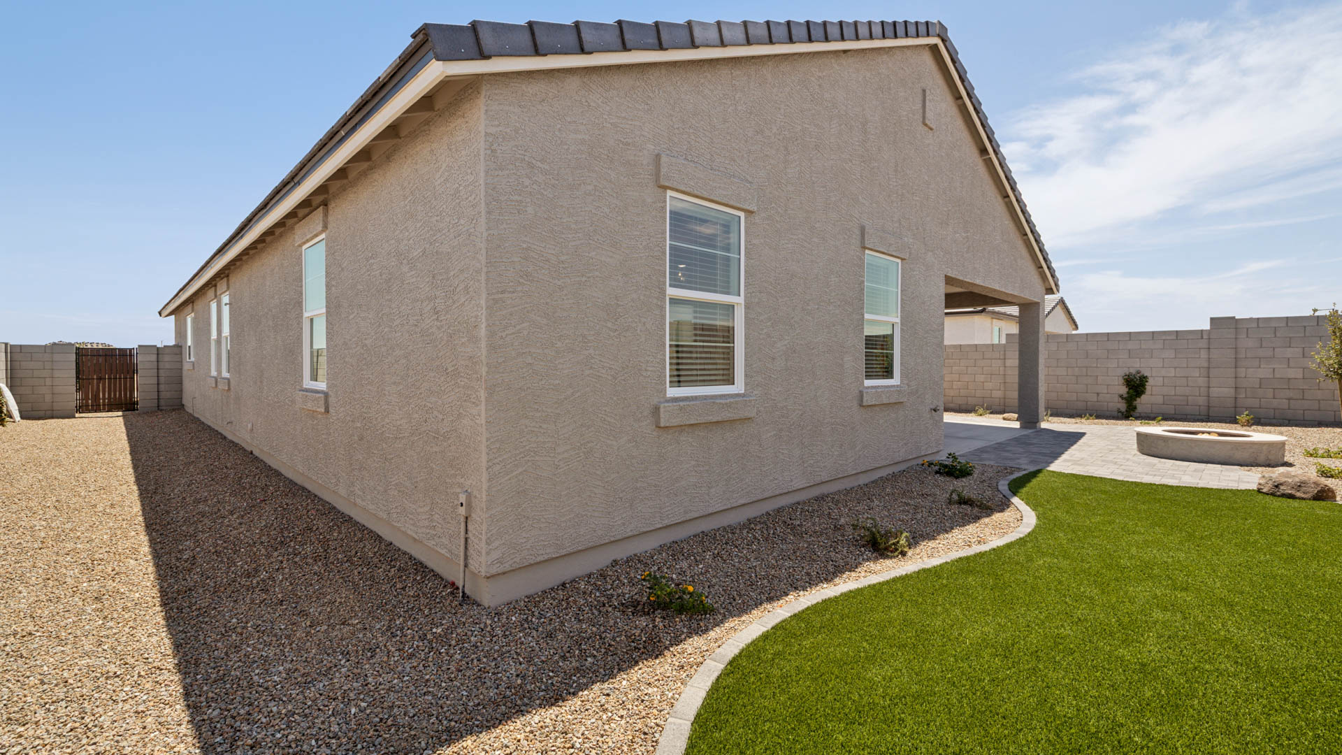Outdoor covered patio with seating area overlooking a well-maintained lawn, perfect for relaxation.