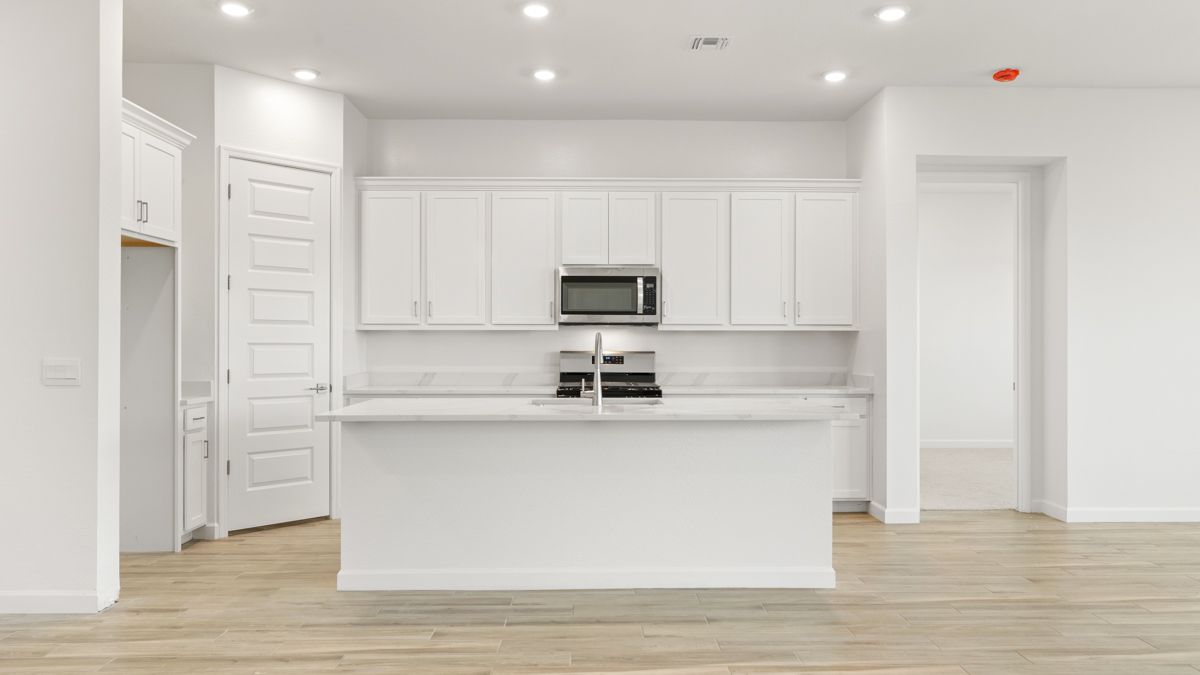 Bright and spacious kitchen with quartz countertops, stainless steel appliances, and an island with bar seating.