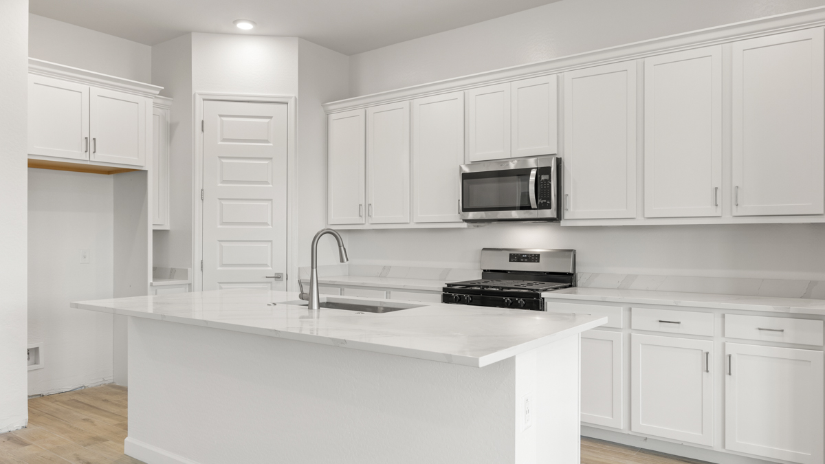Bright and spacious kitchen with quartz countertops, stainless steel appliances, and an island with bar seating.