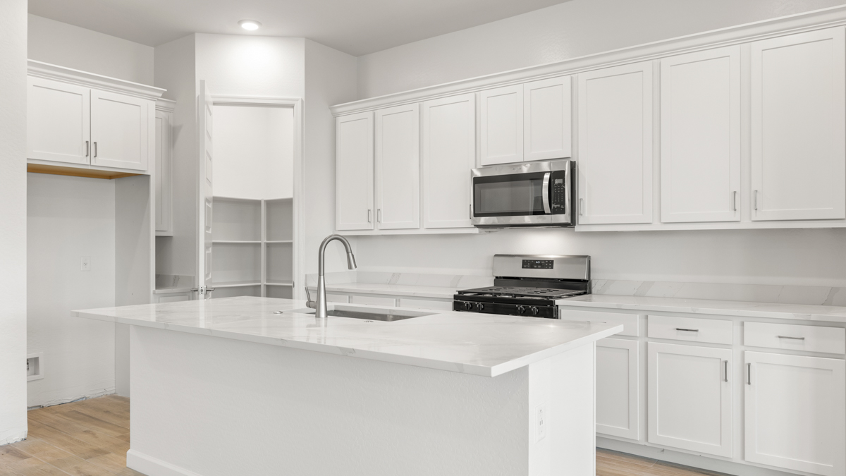 Bright and spacious kitchen with quartz countertops, stainless steel appliances, and an island with bar seating.