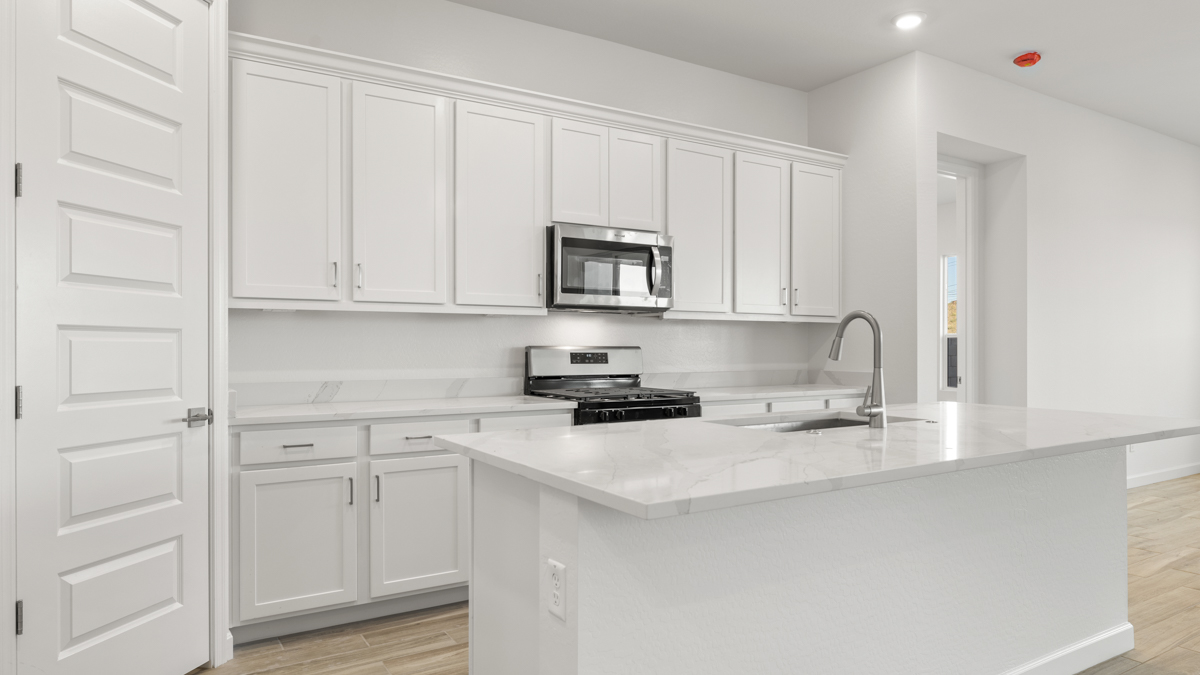 Bright and spacious kitchen with quartz countertops, stainless steel appliances, and an island with bar seating.