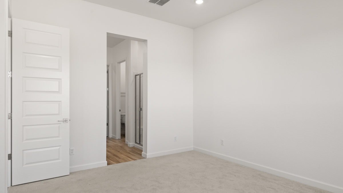A spacious primary bedroom emphasizing open space and natural lighting.