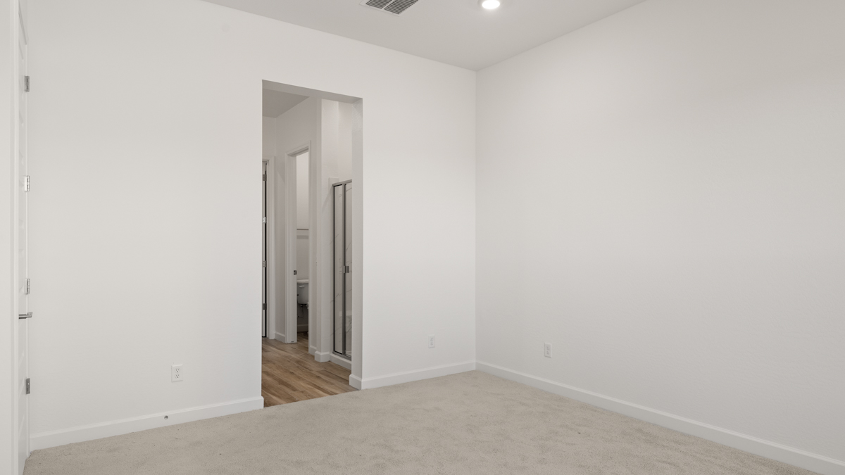 A spacious primary bedroom emphasizing open space and natural lighting.