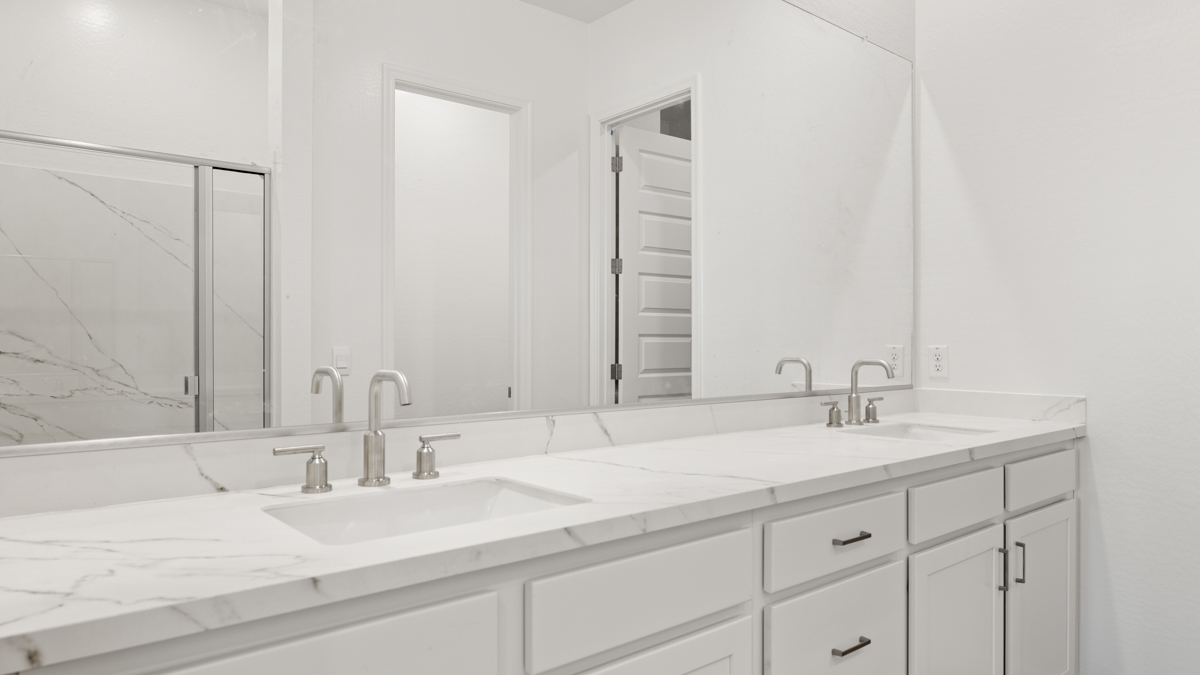 Modern primary bathroom with double vanities, quartz countertops with a walk-in shower and a walk-in closet.