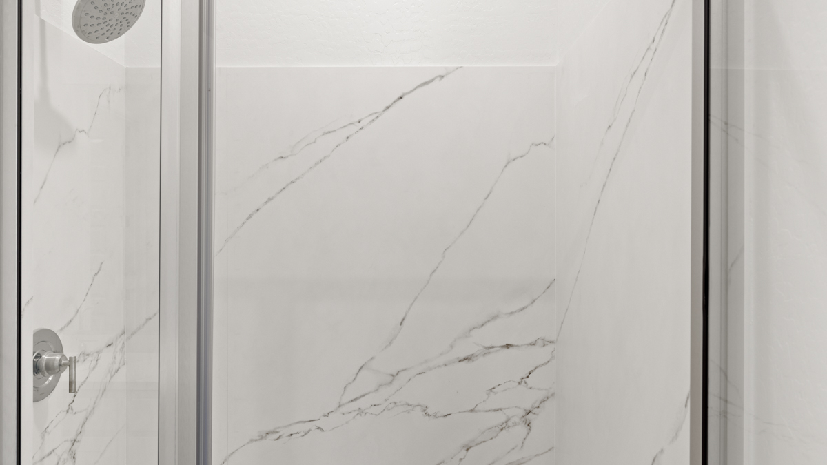 Modern primary bathroom with double vanities, quartz countertops with a walk-in shower and a walk-in closet.