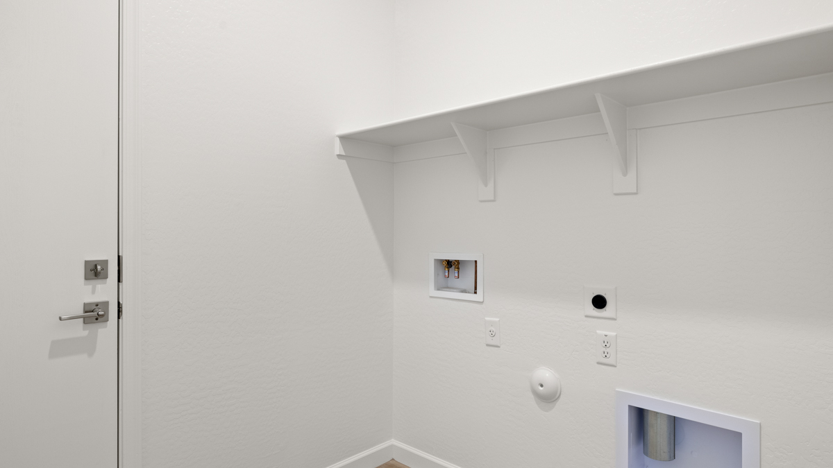 Spacious laundry room with washer and dryer connections and shelving for storage.