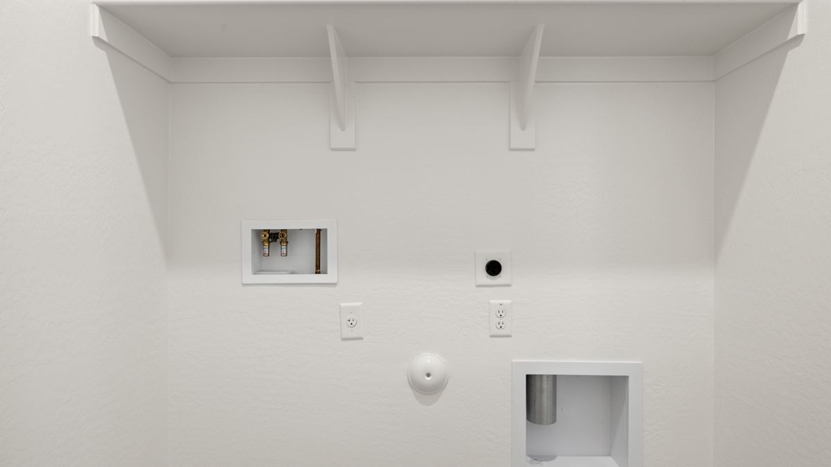 Spacious laundry room with washer and dryer connections and shelving for storage.