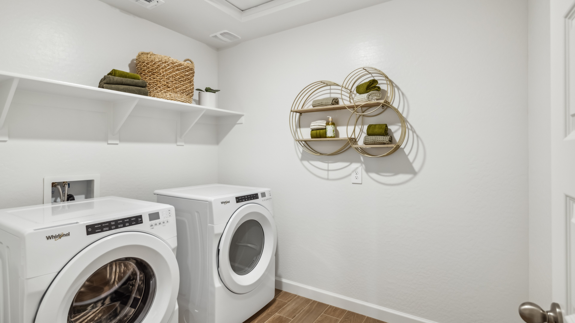 Spacious laundry room with washer and dryer connections and shelving for storage.