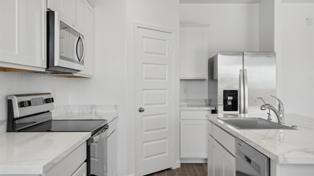 Other side view of kitchen with cabinets, dining, living areas, pantry, appliance suite included