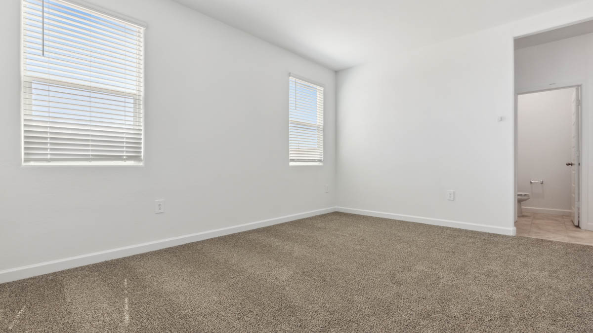 A spacious primary bedroom emphasizing open space and natural lighting.
