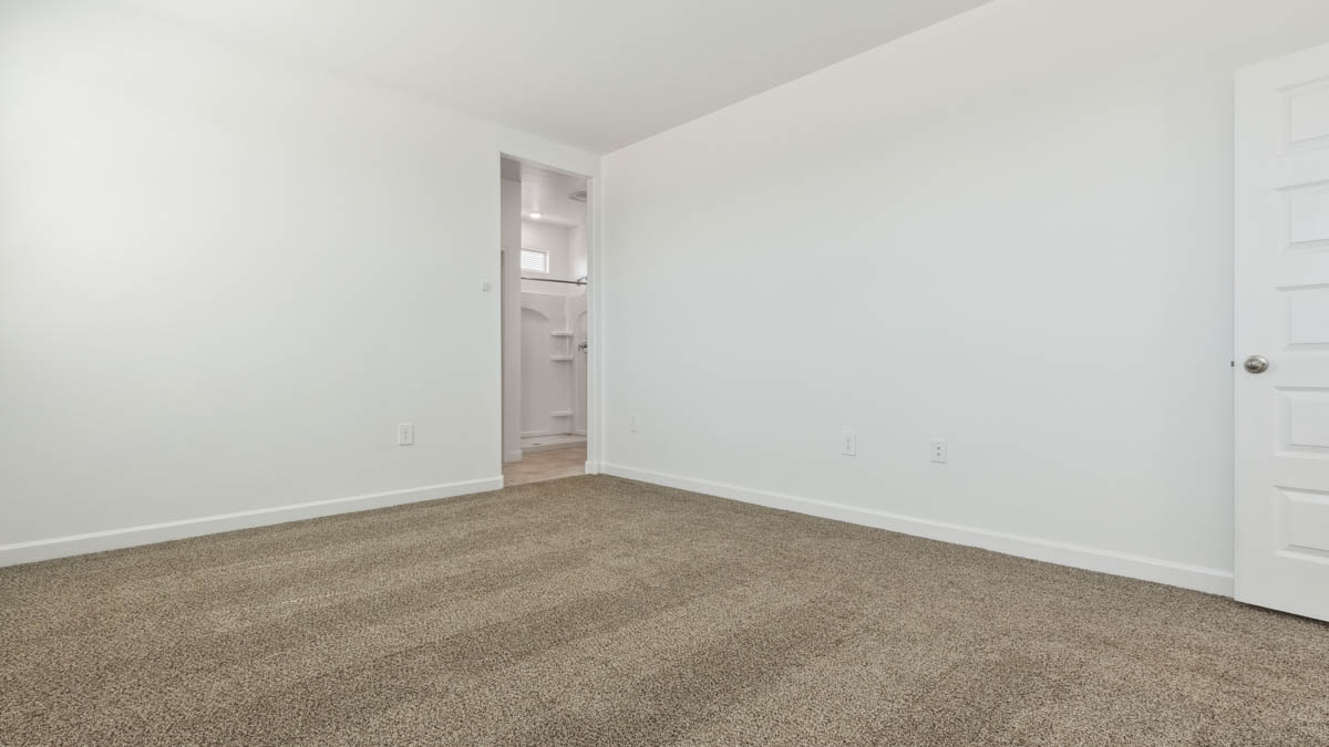 A spacious primary bedroom emphasizing open space and natural lighting.