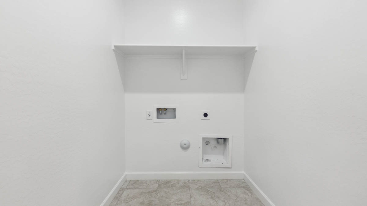 Spacious laundry room with washer and dryer connections and shelving for storage.
