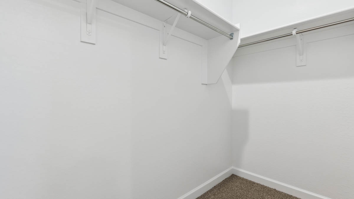 Modern primary bathroom with double vanity, granite countertops with a walk-in shower and a walk-in closet.