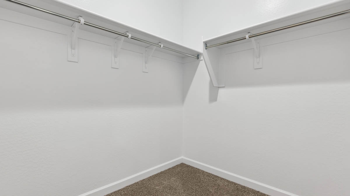 Modern primary bathroom with double vanity, granite countertops with a walk-in shower and a walk-in closet.