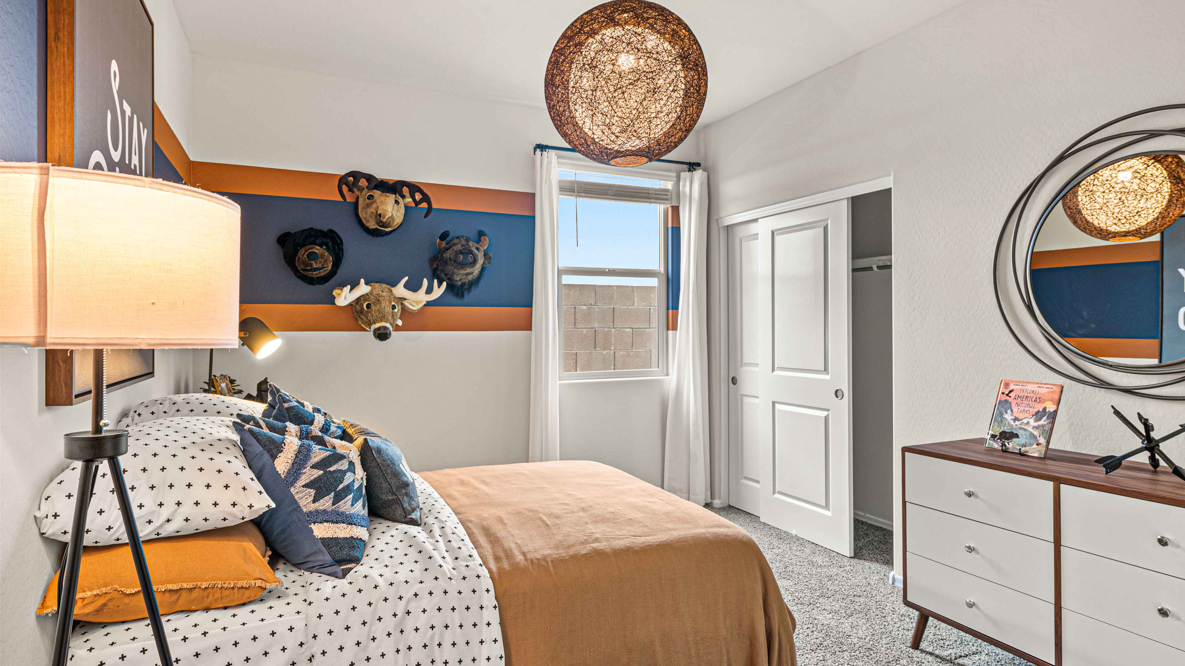 A vibrant kids' bedroom showcasing a neatly made bed, a stylish dresser, and a playful painting that adds charm.