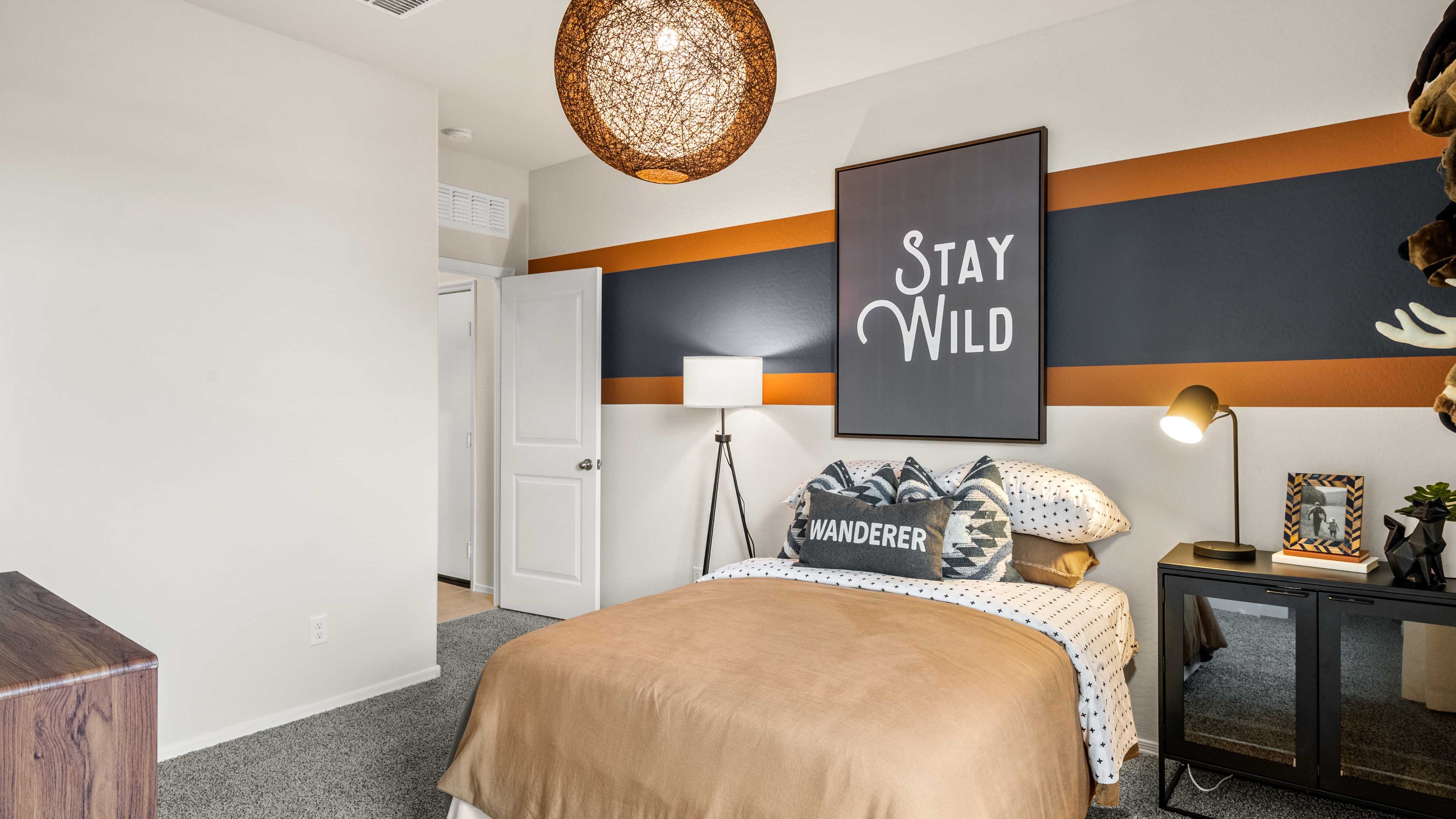 A vibrant kids' bedroom showcasing a neatly made bed, a stylish dresser, and a playful painting that adds charm.