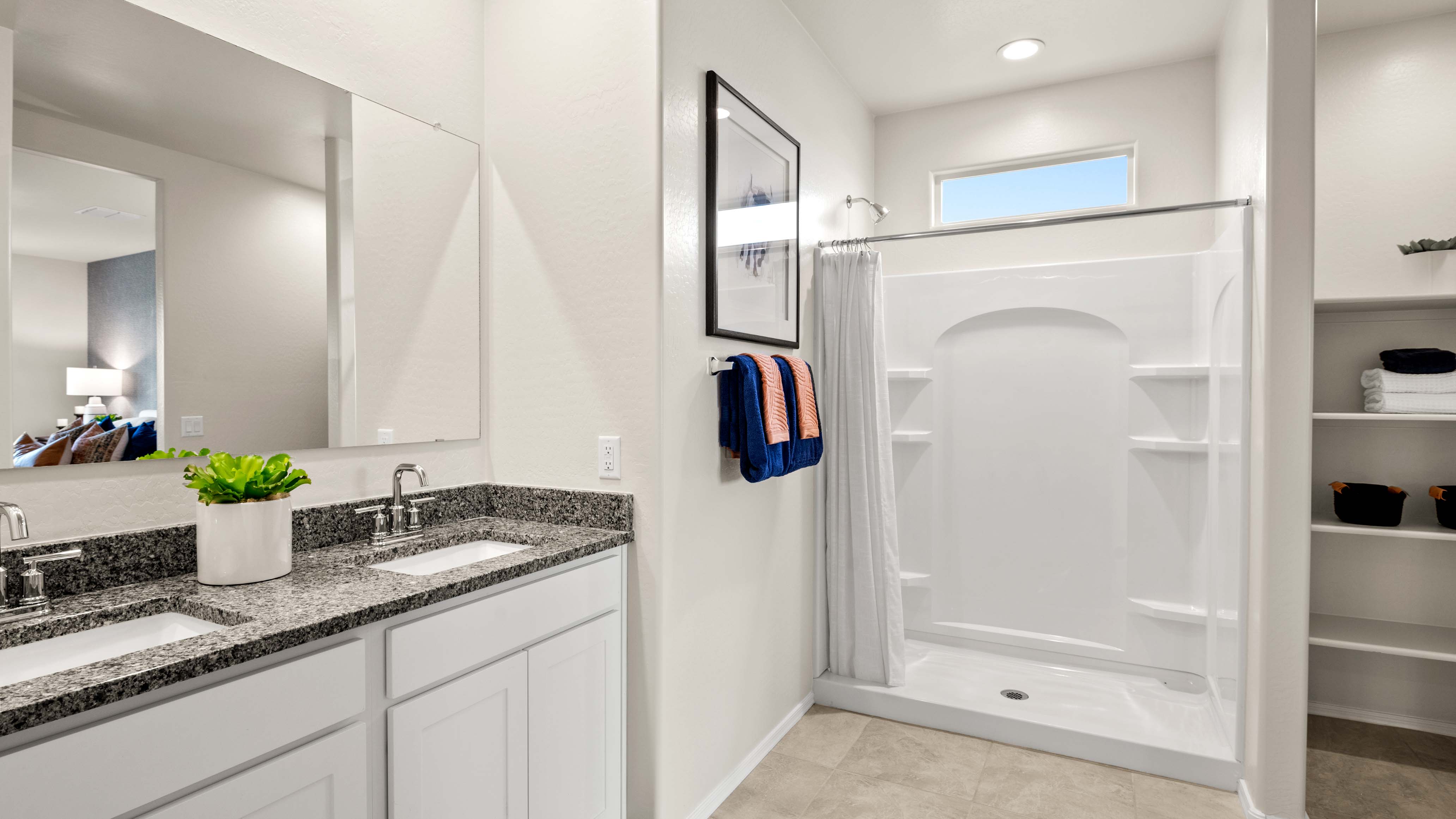 Modern primary bathroom with double vanity, granite countertops with a walk-in shower and a walk-in closet.
