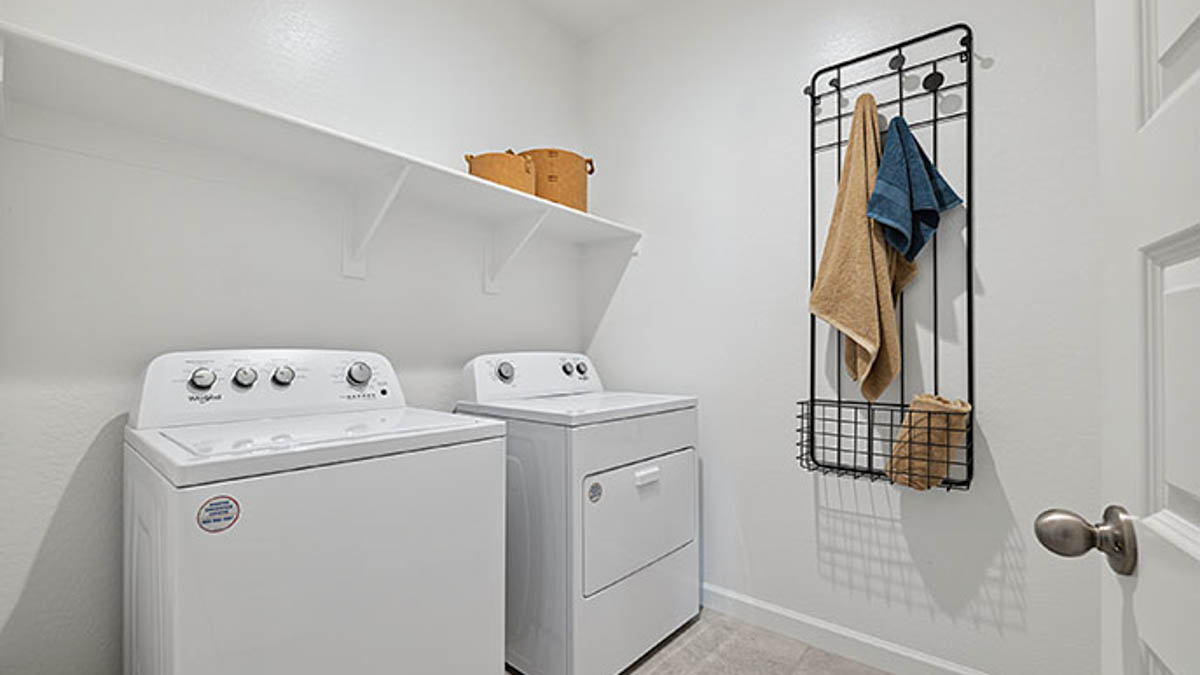 Spacious laundry room with washer and dryer connections and shelving for storage.