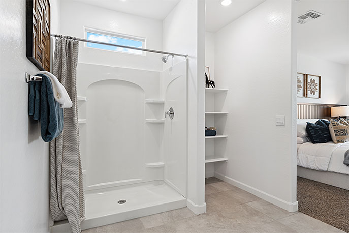 Modern primary bathroom with double vanities, with a walk-in shower and a walk-in closet.