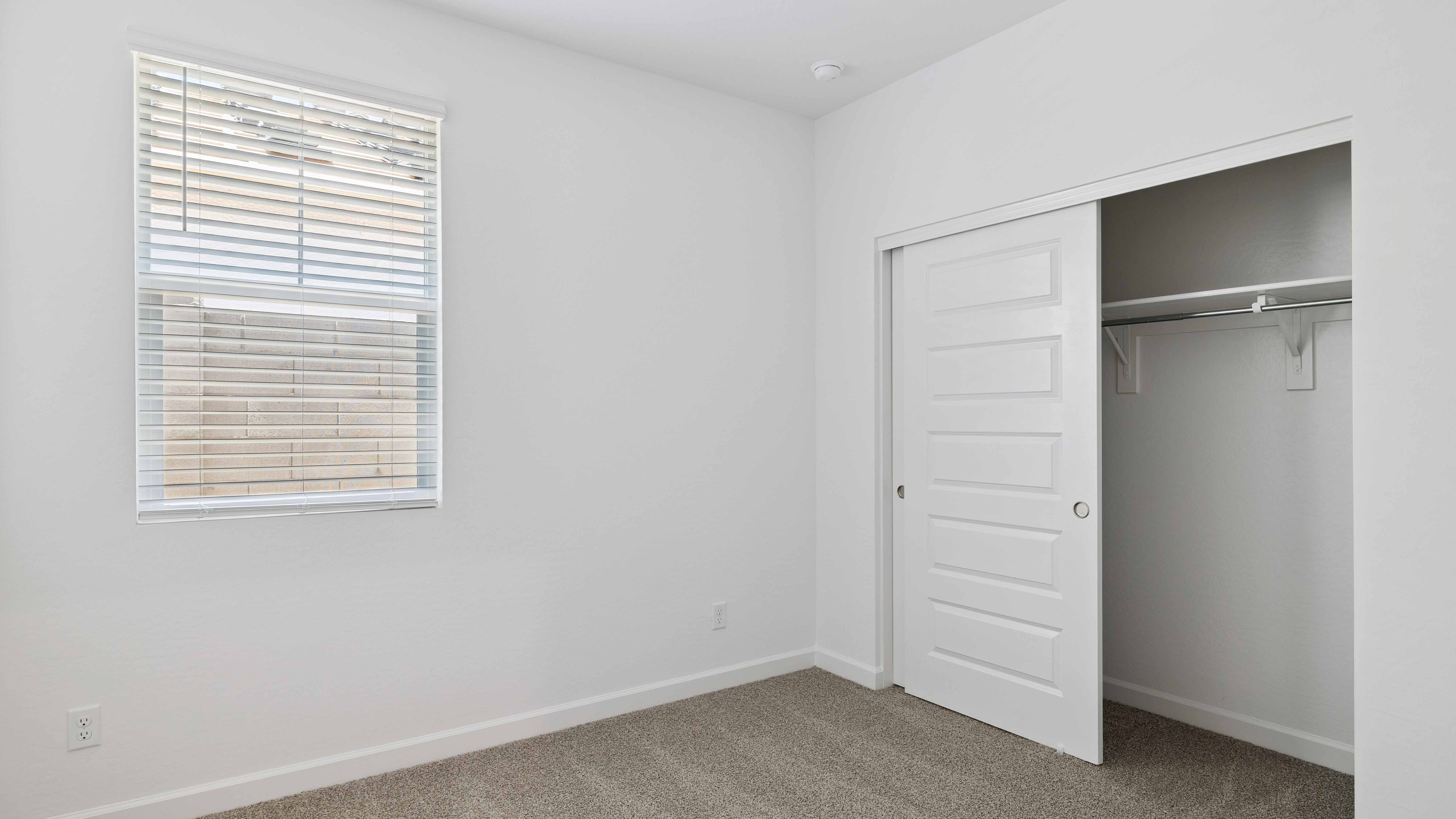 Comfortable guest bedroom featuring neutral-toned walls and a large closet.