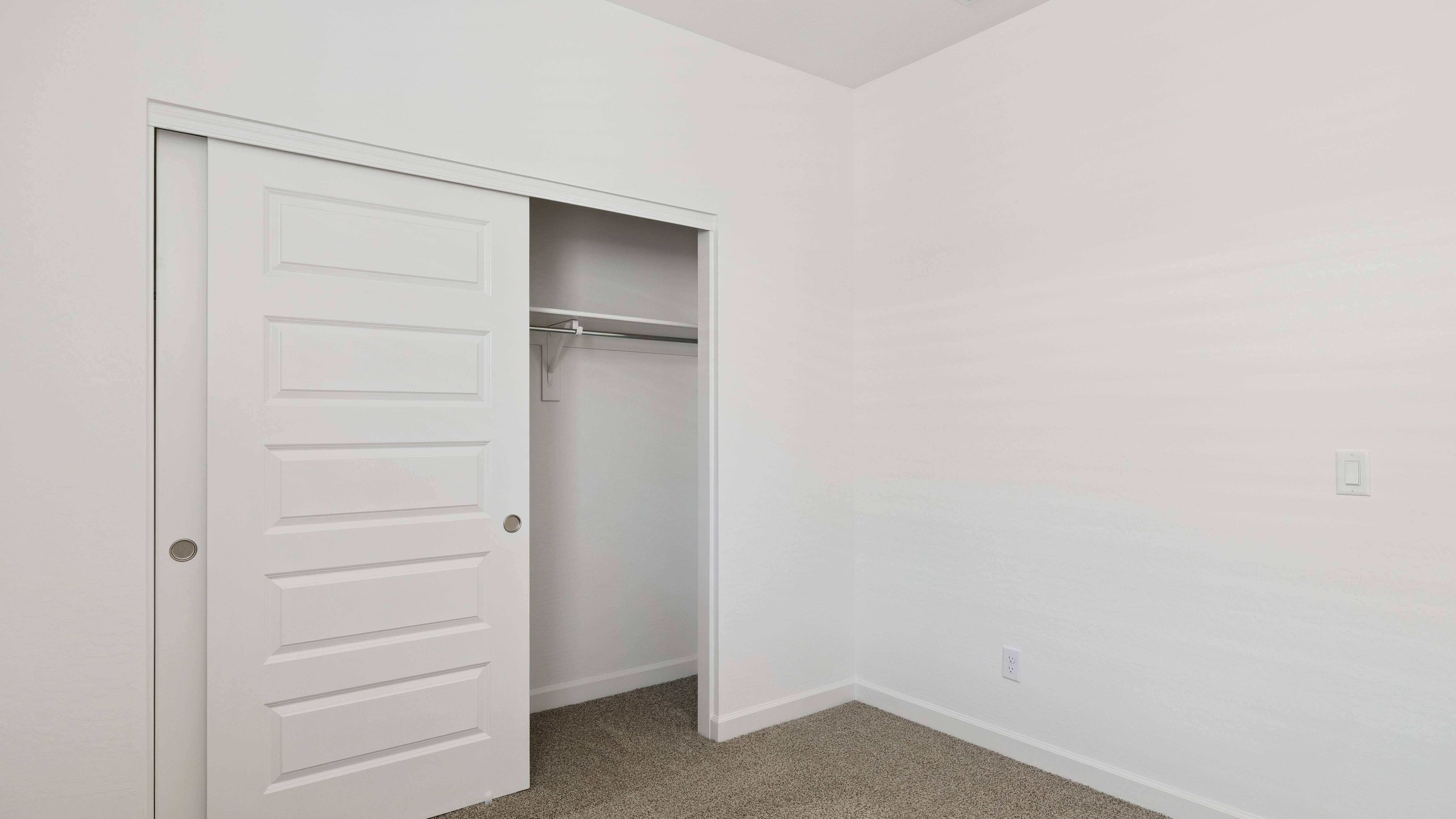 Comfortable guest bedroom featuring neutral-toned walls and a large closet.