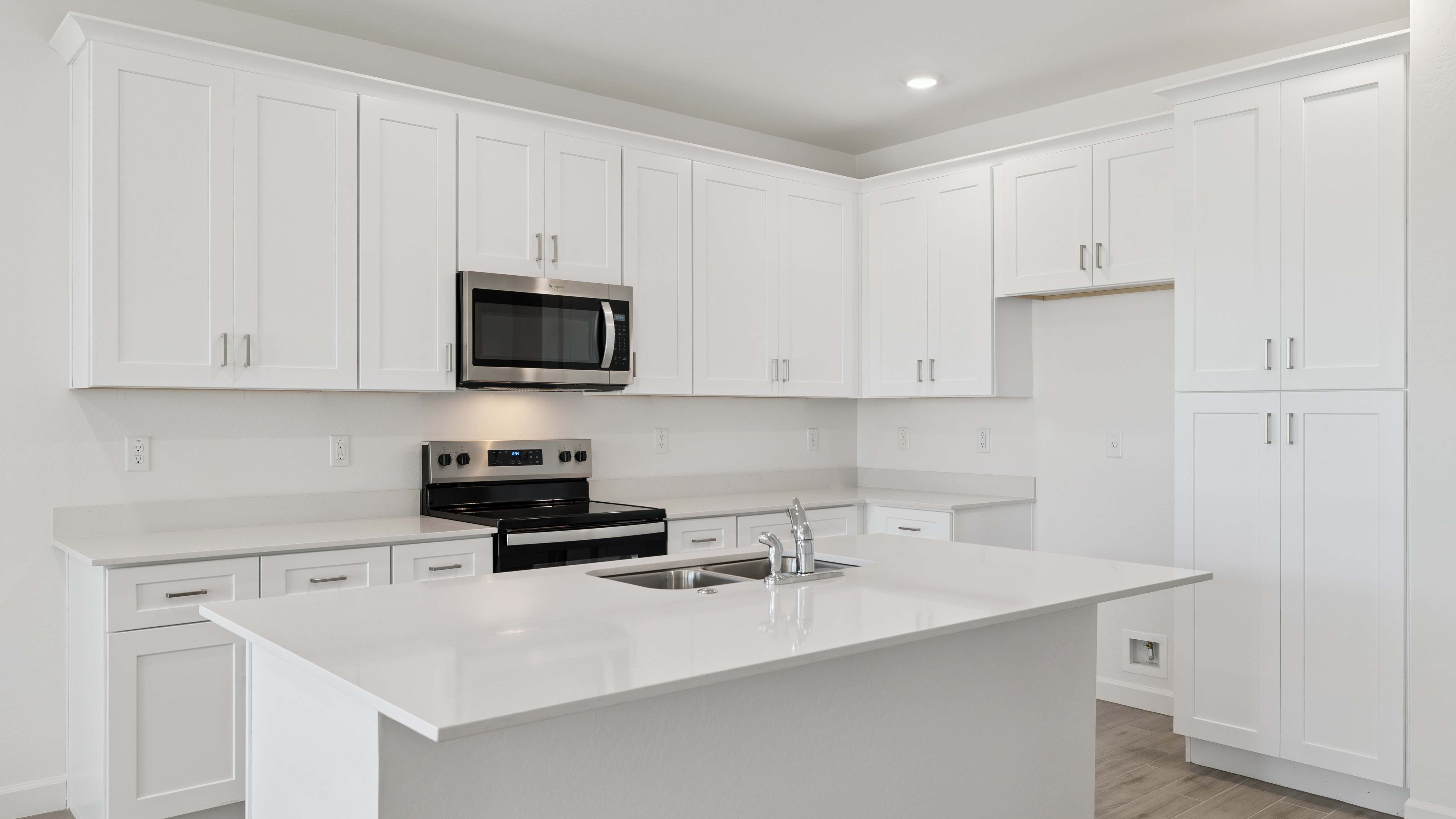Bright and spacious kitchen with quartz countertops, stainless steel appliances, and an island with bar seating.