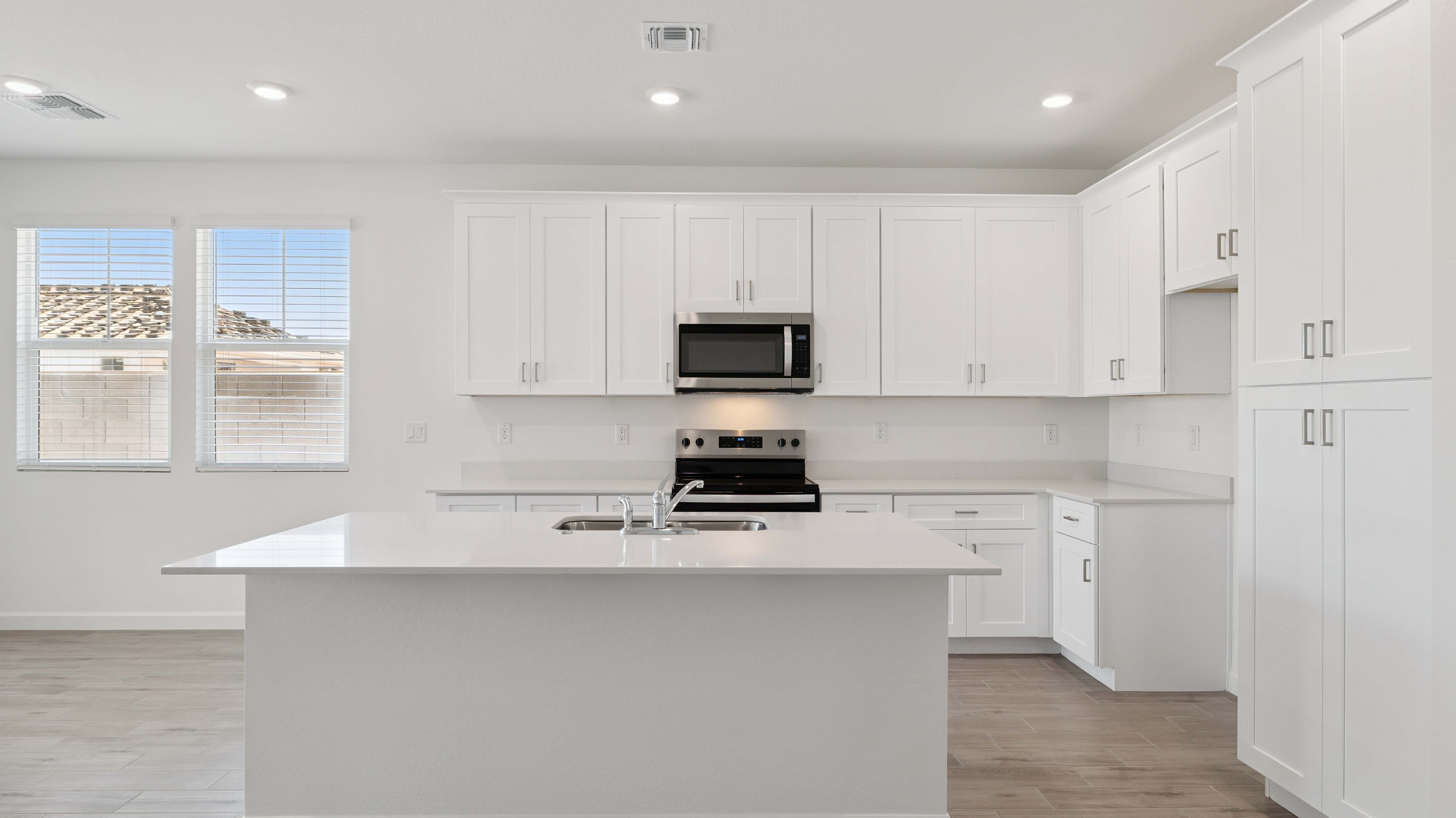 Bright and spacious kitchen with quartz countertops, stainless steel appliances, and an island with bar seating.