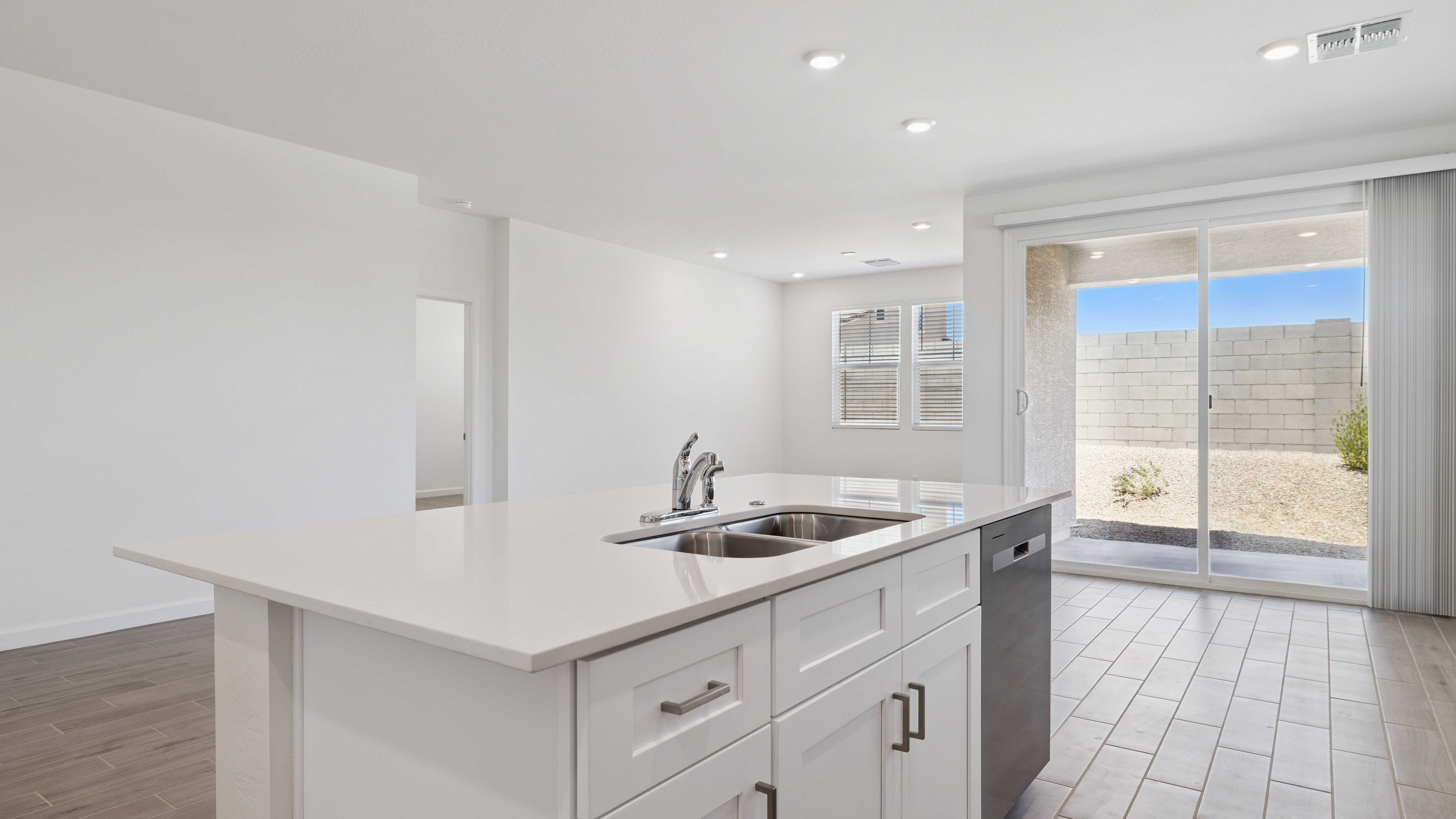 Bright and spacious kitchen with quartz countertops, stainless steel appliances, and an island with bar seating.