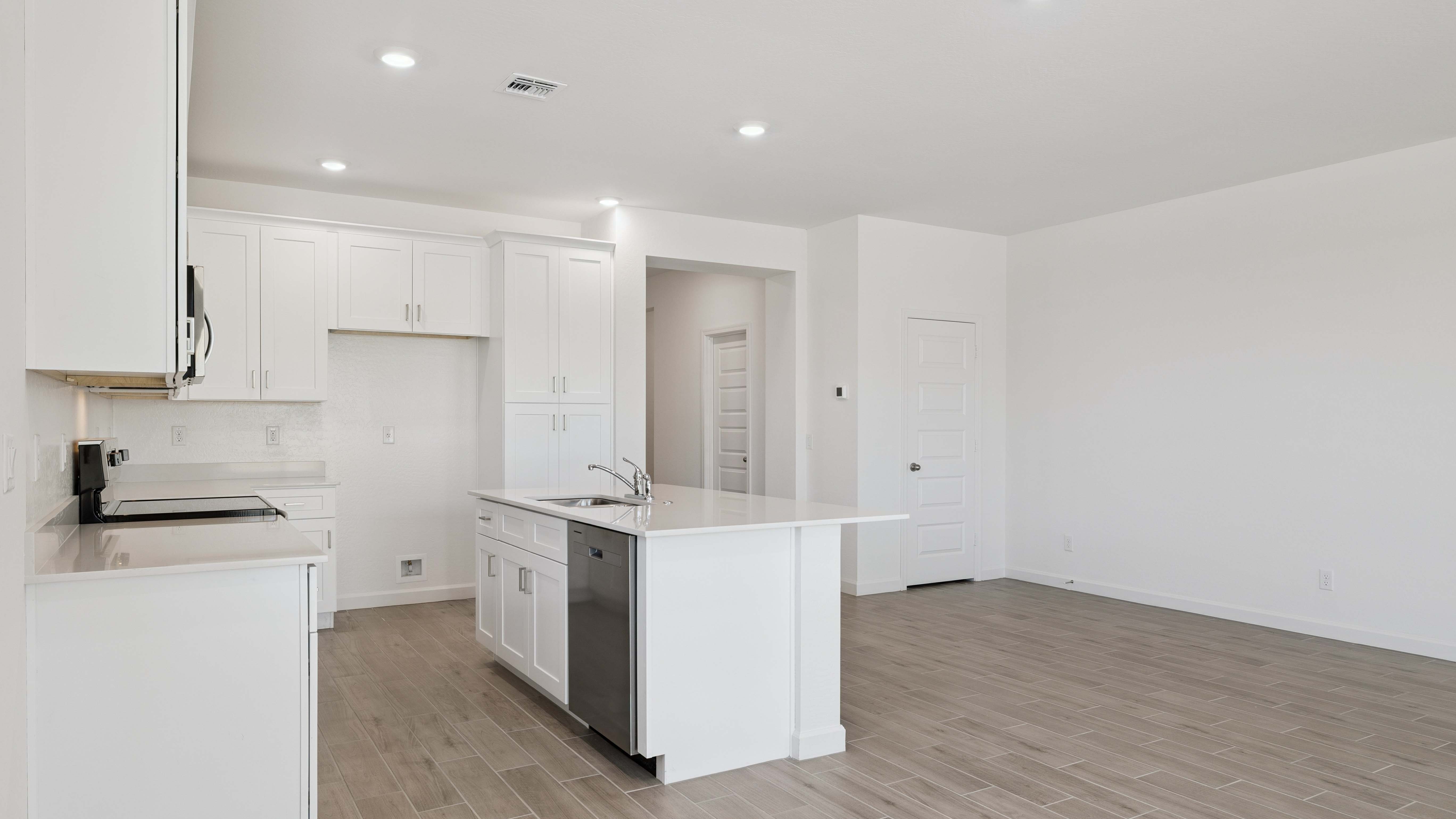 Bright and spacious kitchen with quartz countertops, stainless steel appliances, and an island with bar seating.