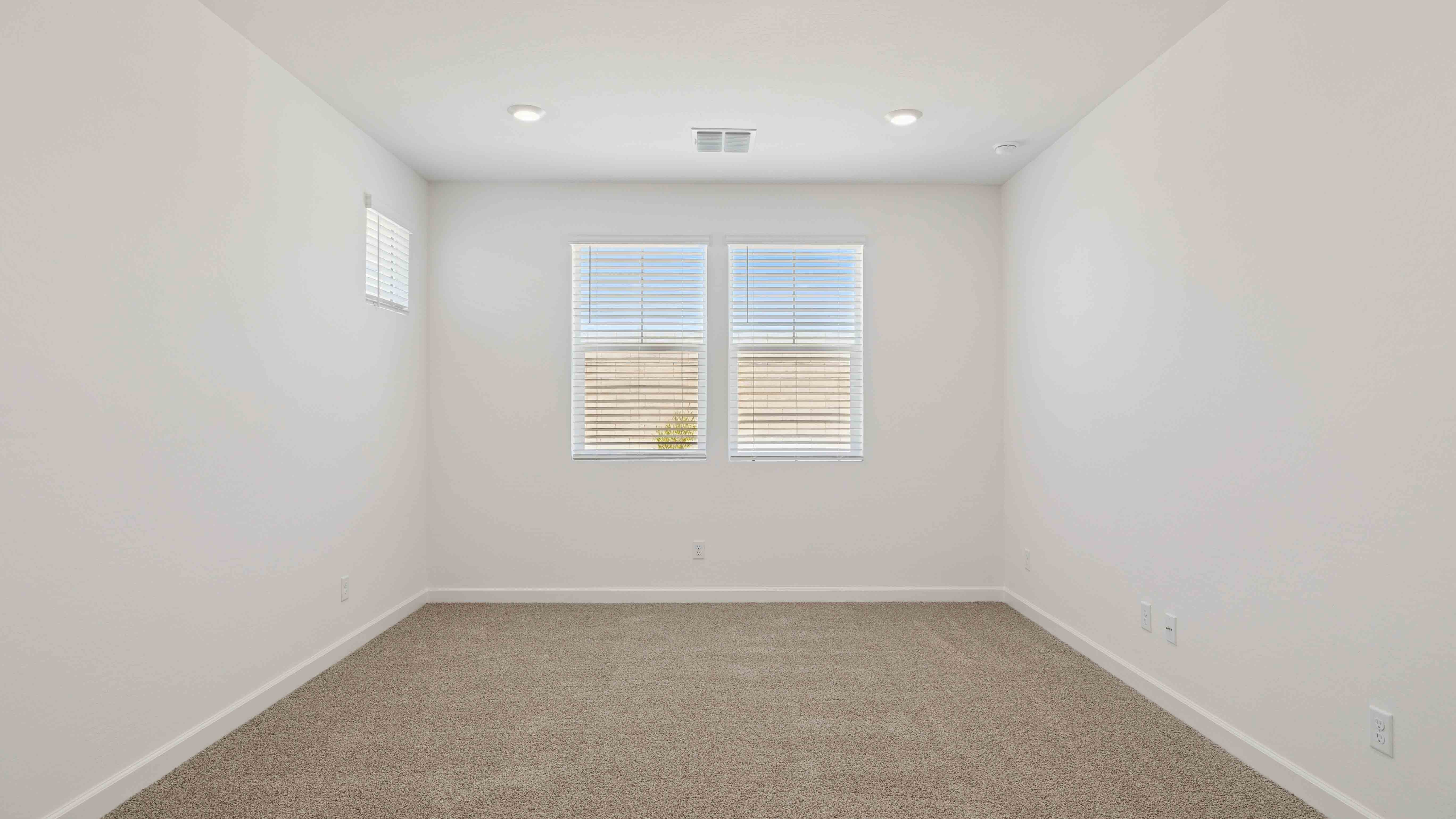 A spacious primary bedroom emphasizing open space and natural lighting.