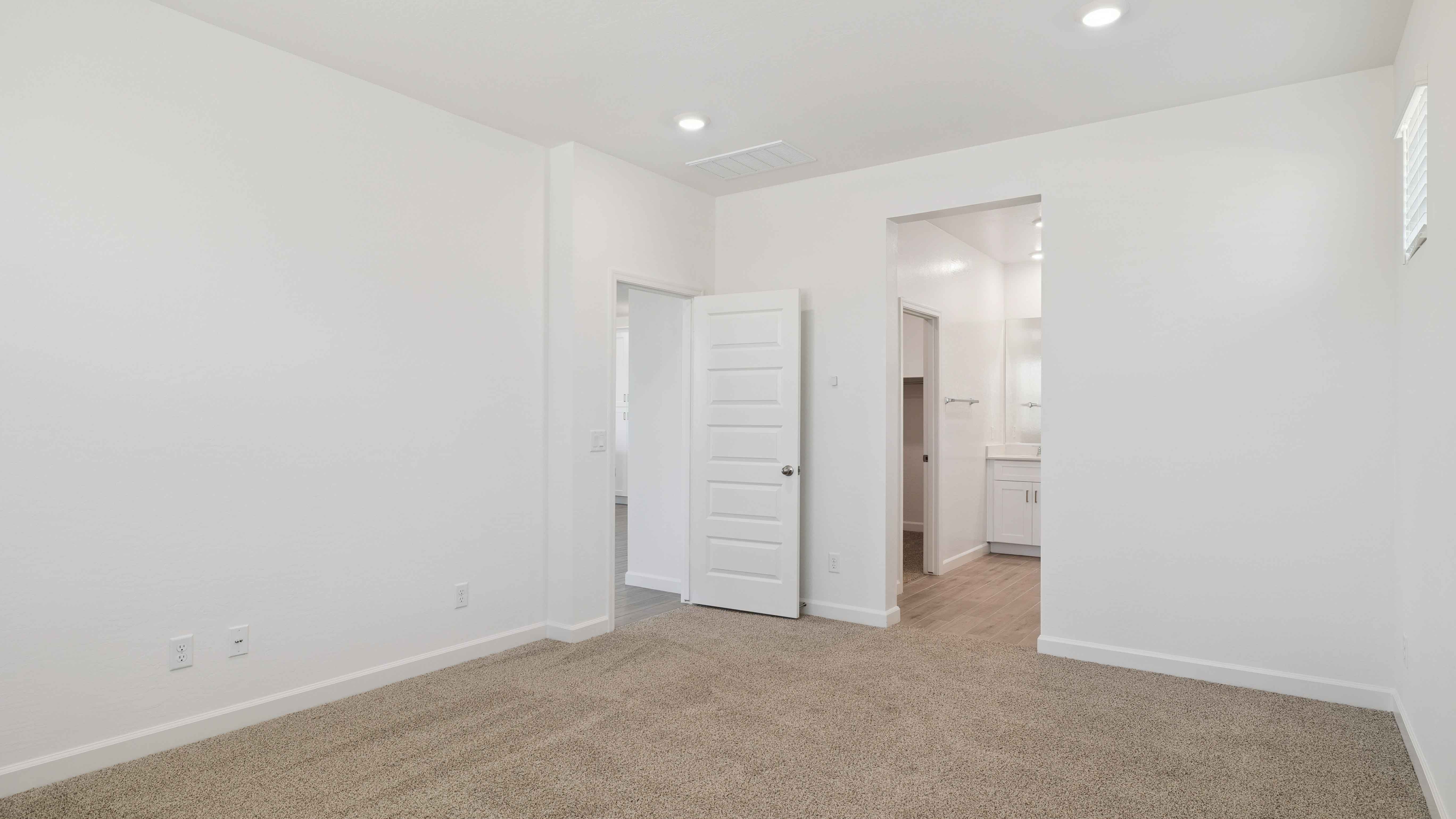 A spacious primary bedroom emphasizing open space and natural lighting.