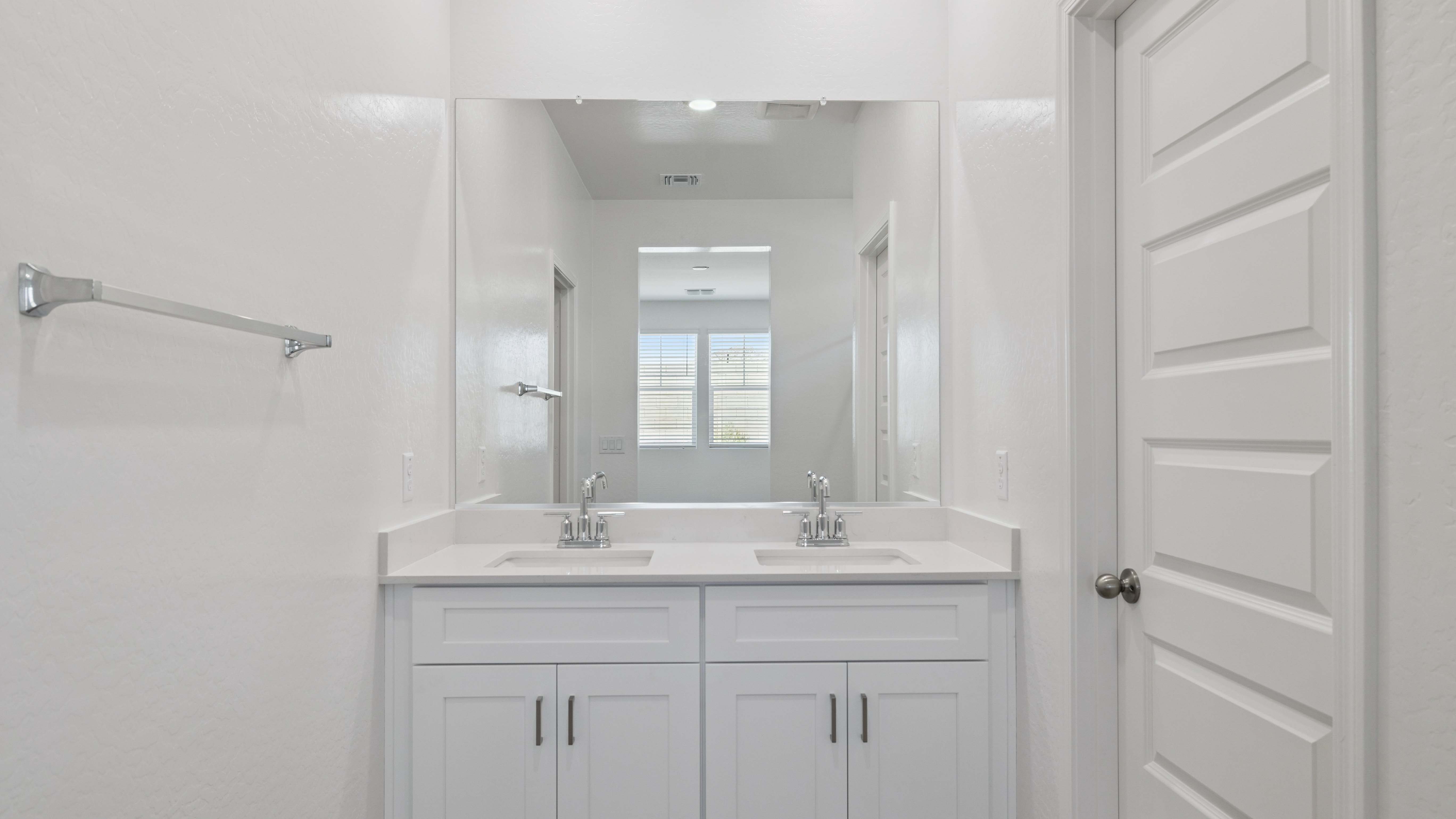 Modern primary bathroom with double vanities, quartz countertops with a walk-in shower and a walk-in closet.
