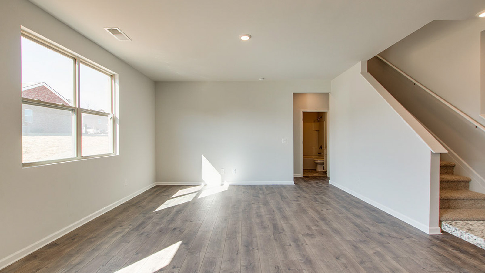 Living room in new, open-concept home with windows and natural lighting