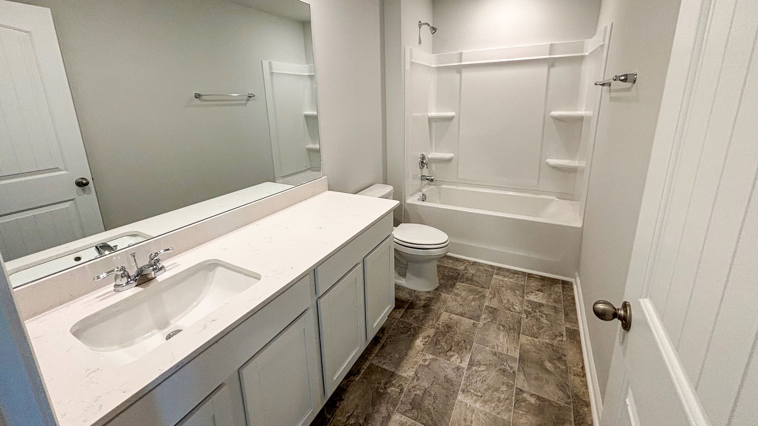Family bathroom with stylish vanity, mirror, polished fixtures, cabinets, tub-shower combo in River Landing