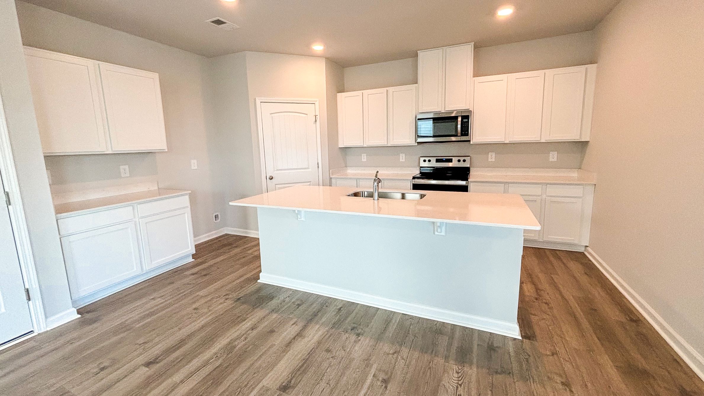 Spacious living room with view into dining and kitchen areas, and outside access at River Landing