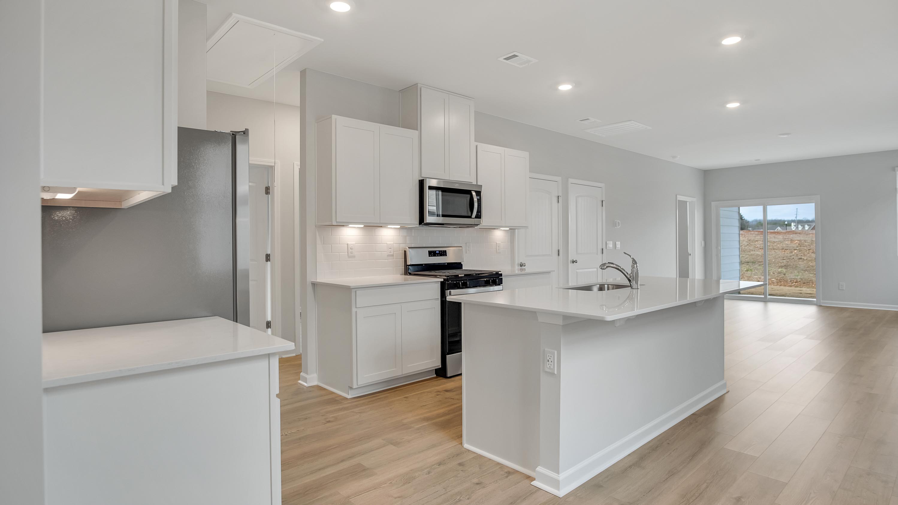 Kitchen island with white cabinets and stainless steel appliances.