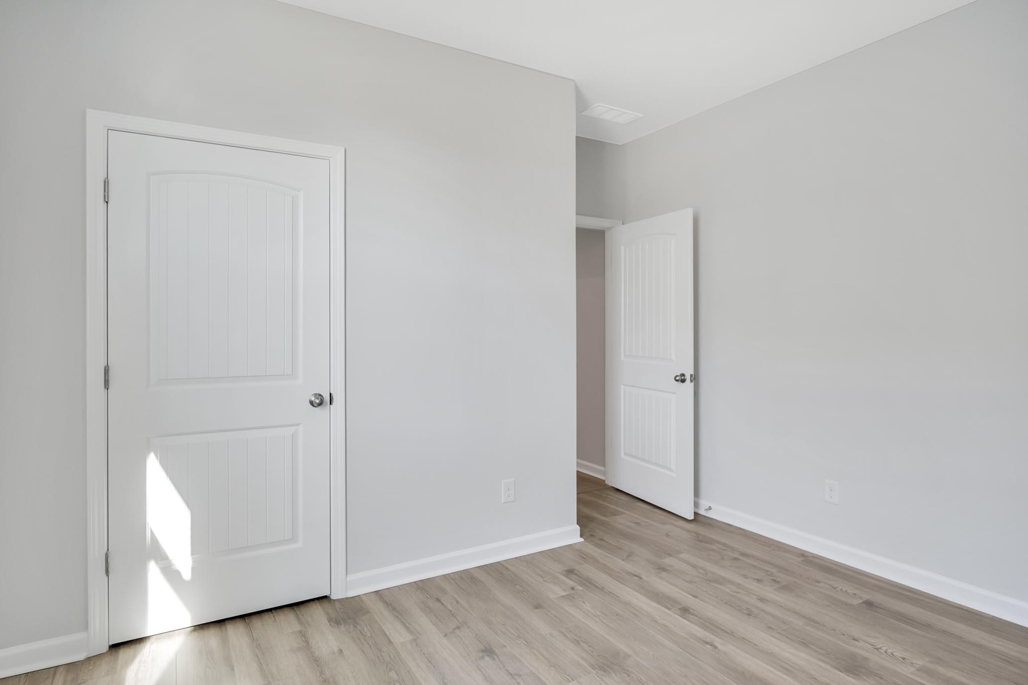 Bedroom with closet and brown flooring.