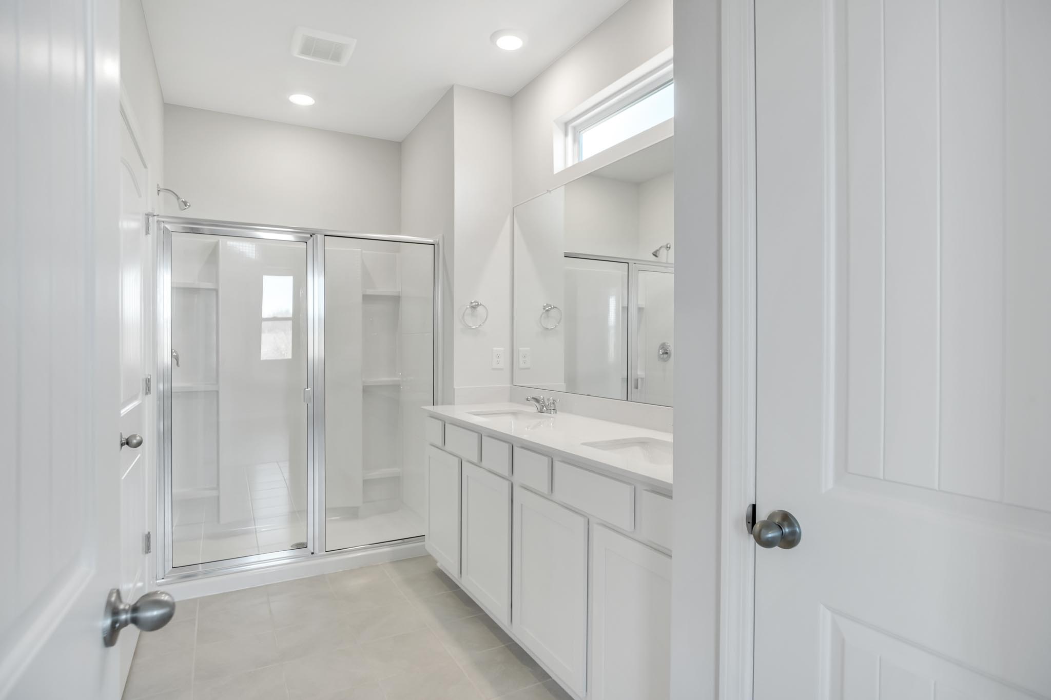 Bathroom with step in shower with glass doors.