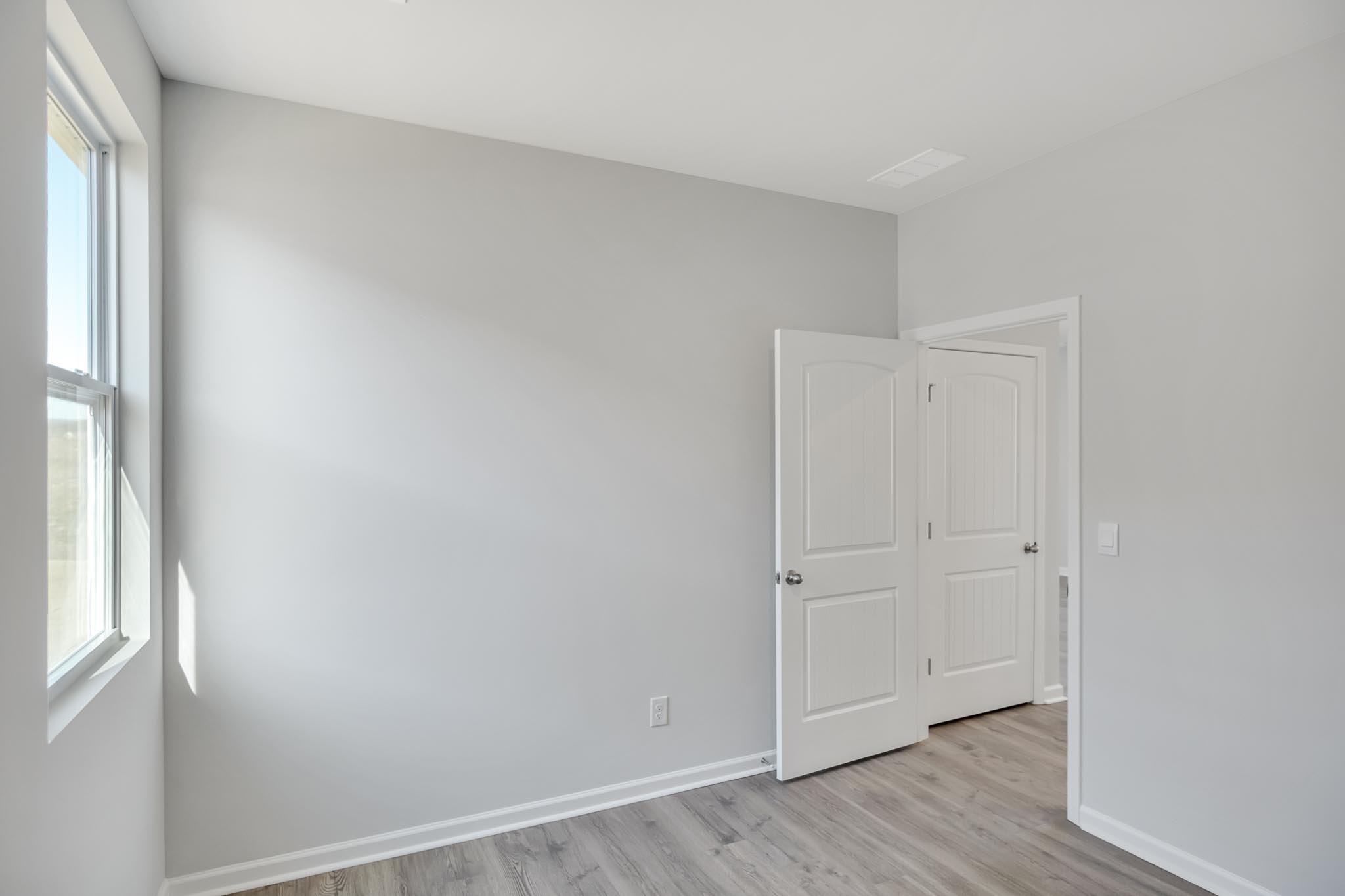 Bedroom with brown flooring and a window.