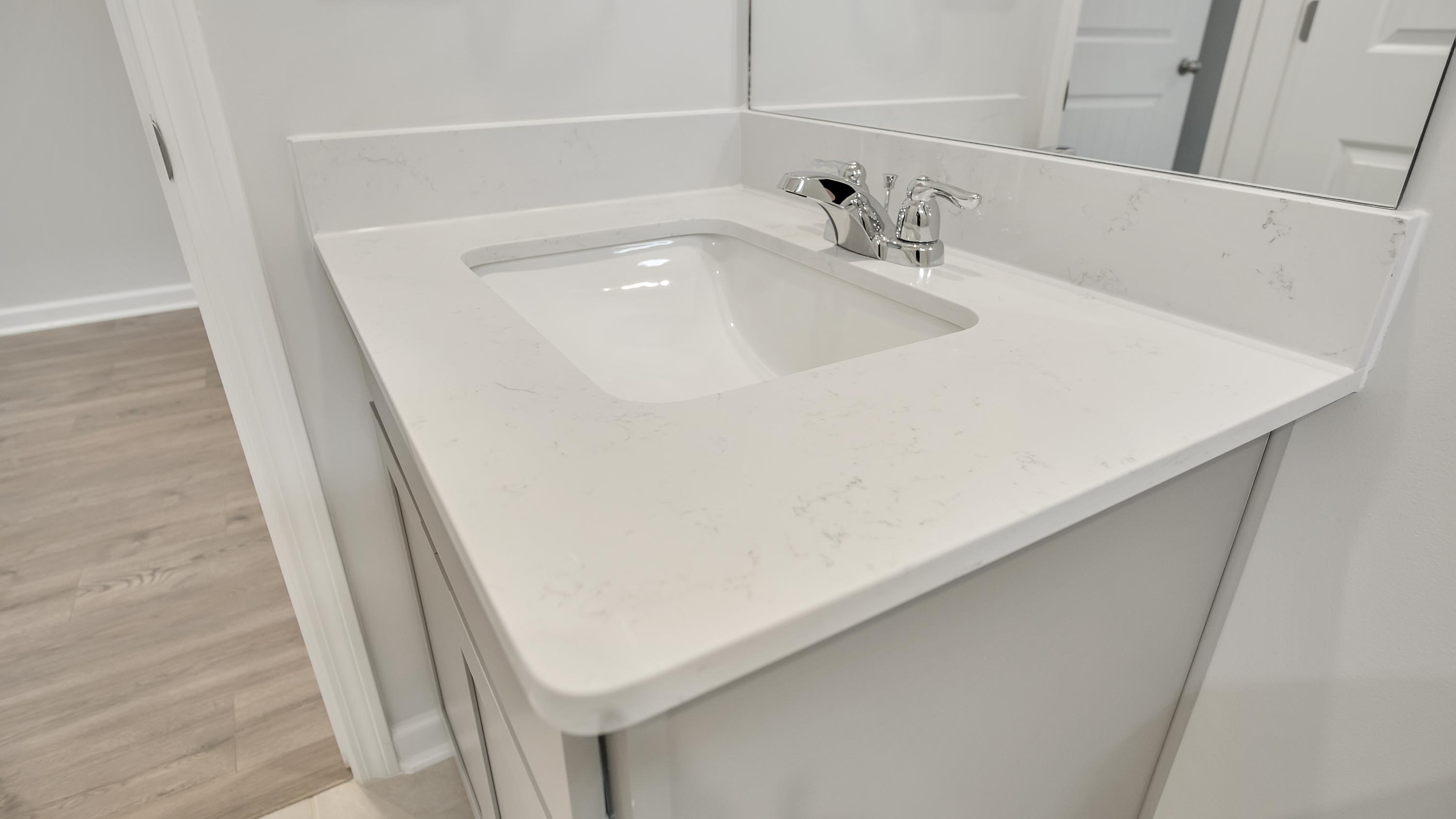 Family bathroom with stylish vanity, mirror, polished fixtures, cabinets, tub-shower combo in Legacy Farms