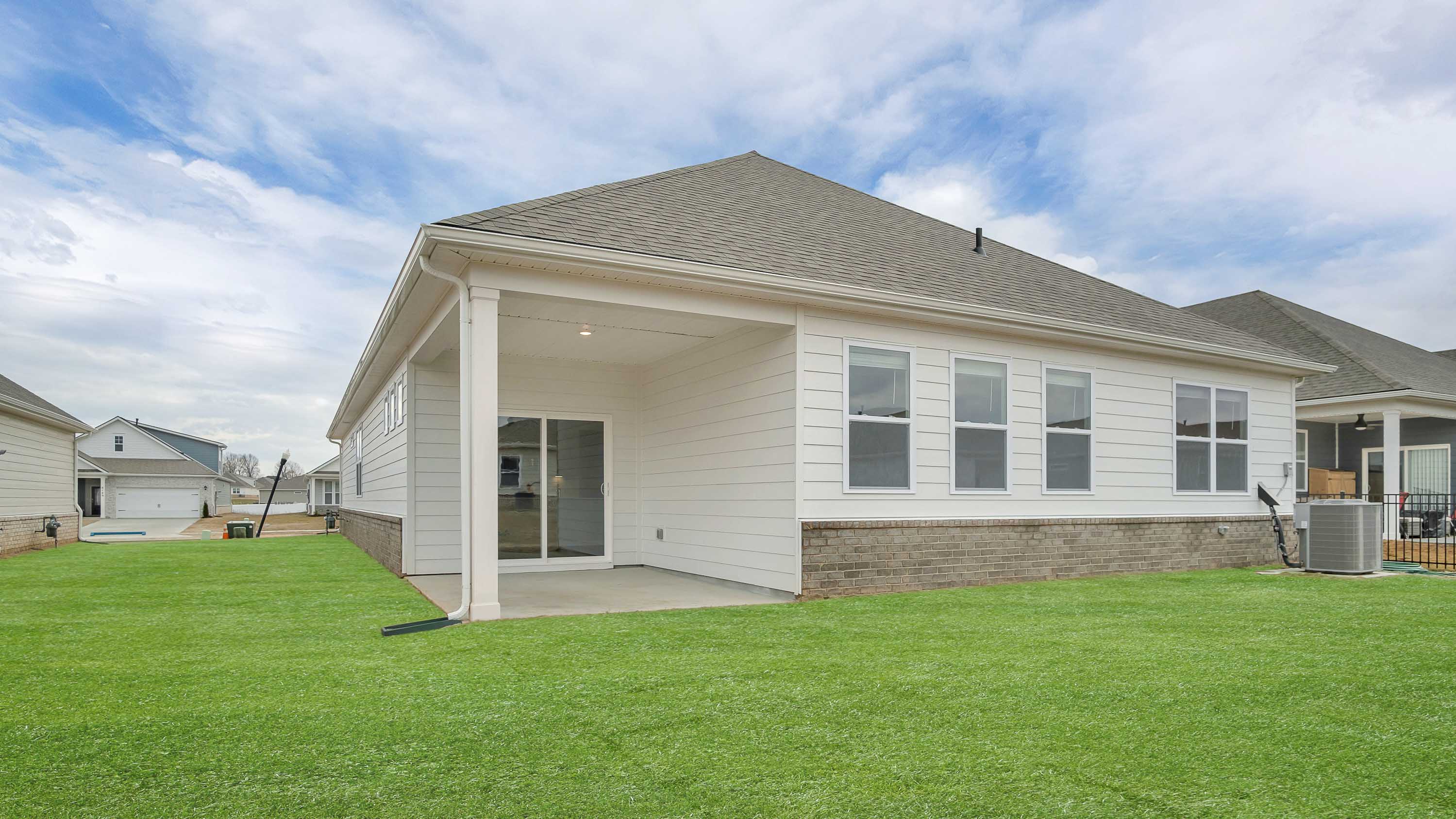 Backyard with covered concrete patio adding seating, grill setup, and a transition from indoor to outdoor life