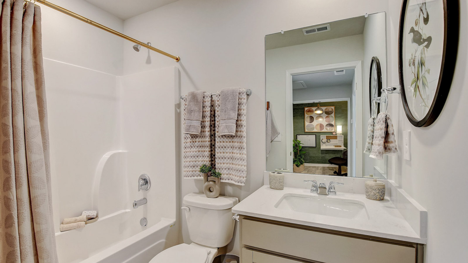 Secondary bathroom adds style and comfort with a combination shower-tub, cabinet storage, vanity, mirror at Saddle Trace Townhomes