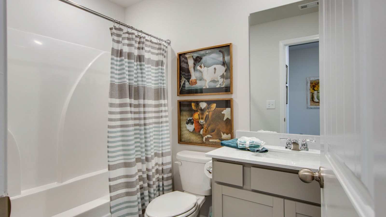 Family bathroom with stylish vanity, mirror, polished fixtures, cabinets, tub-shower combo in King's Landing