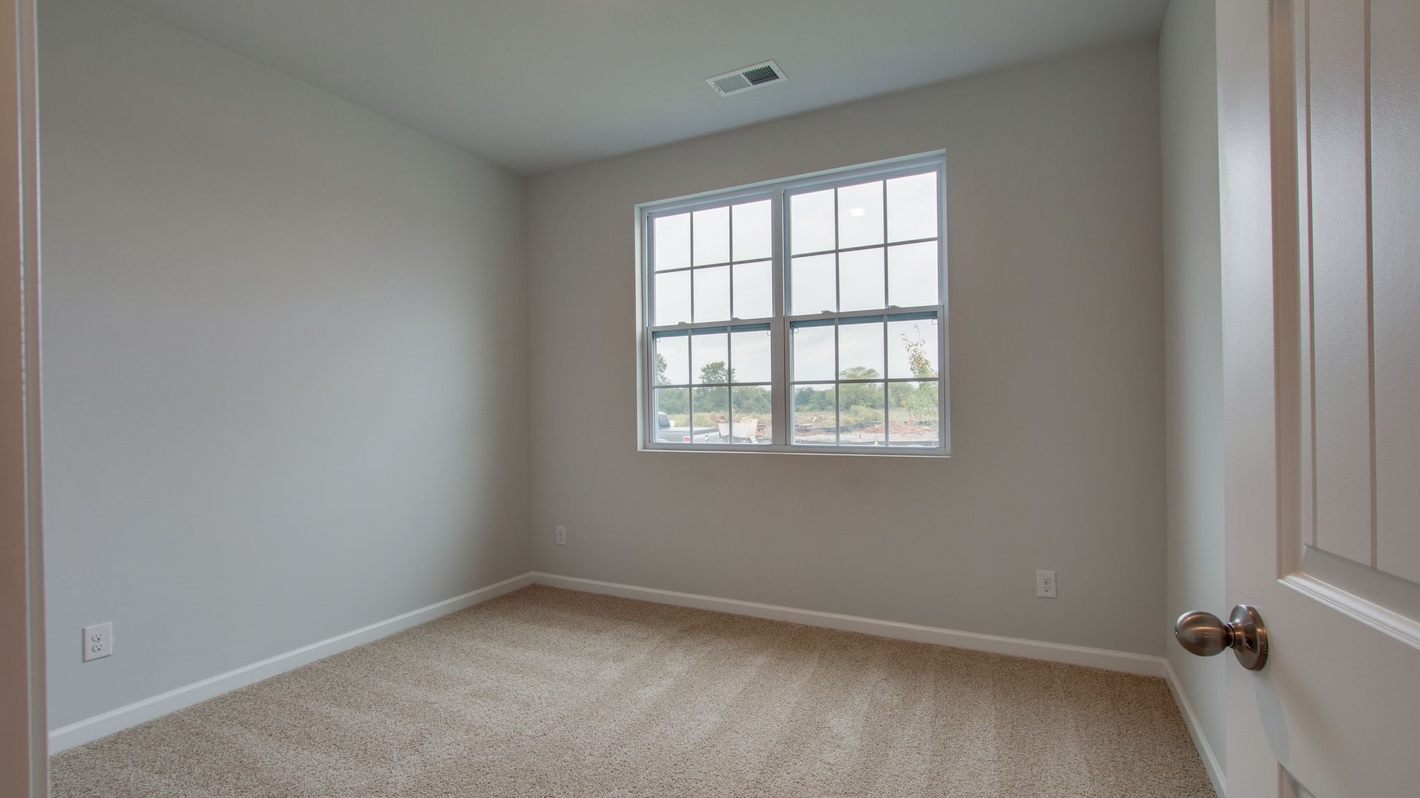 Bedroom with neutral walls, carpet, and a window.
