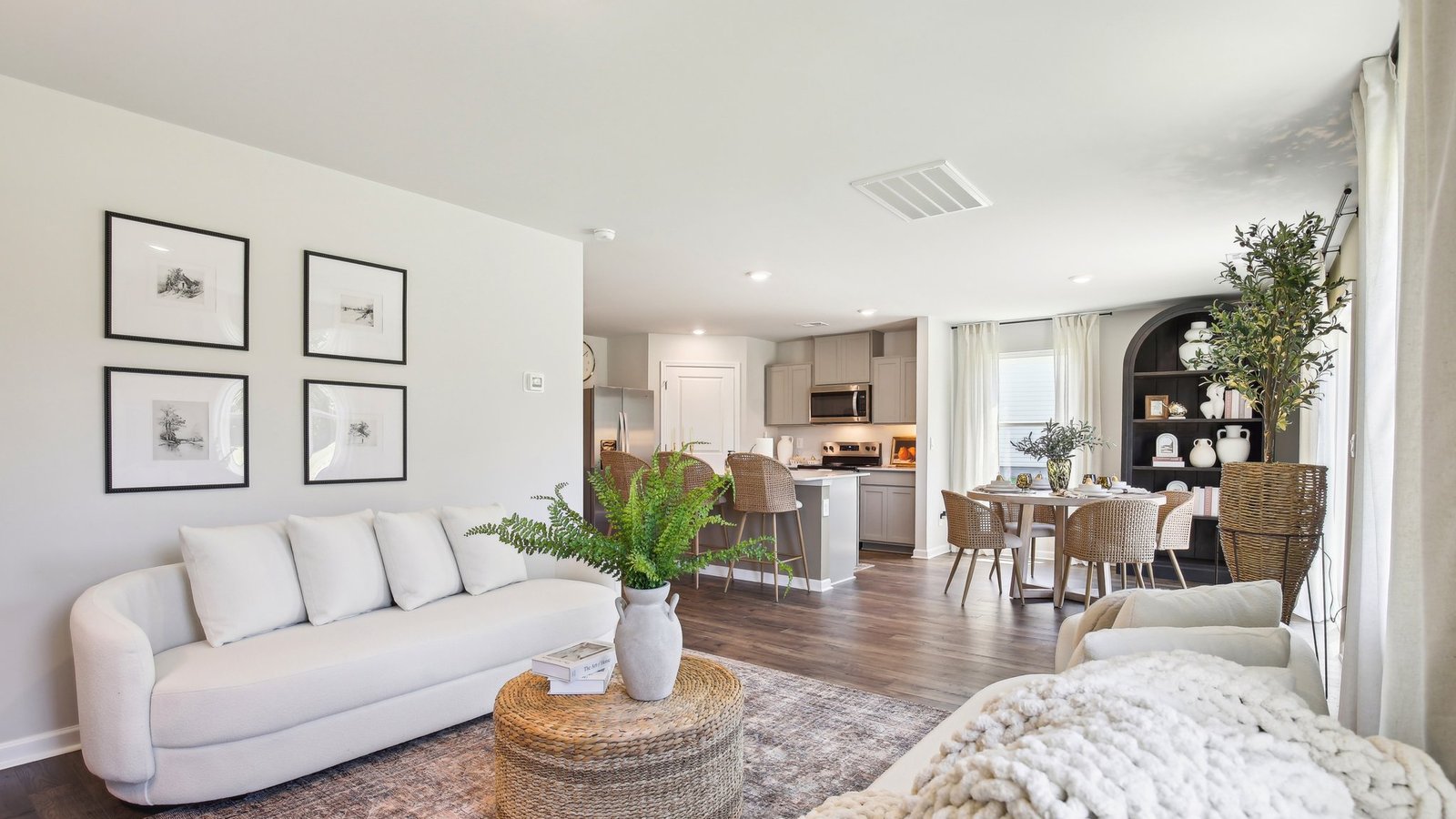 Living room looking to dining and kitchen areas in this new home features natural light, with fresh open concept flow