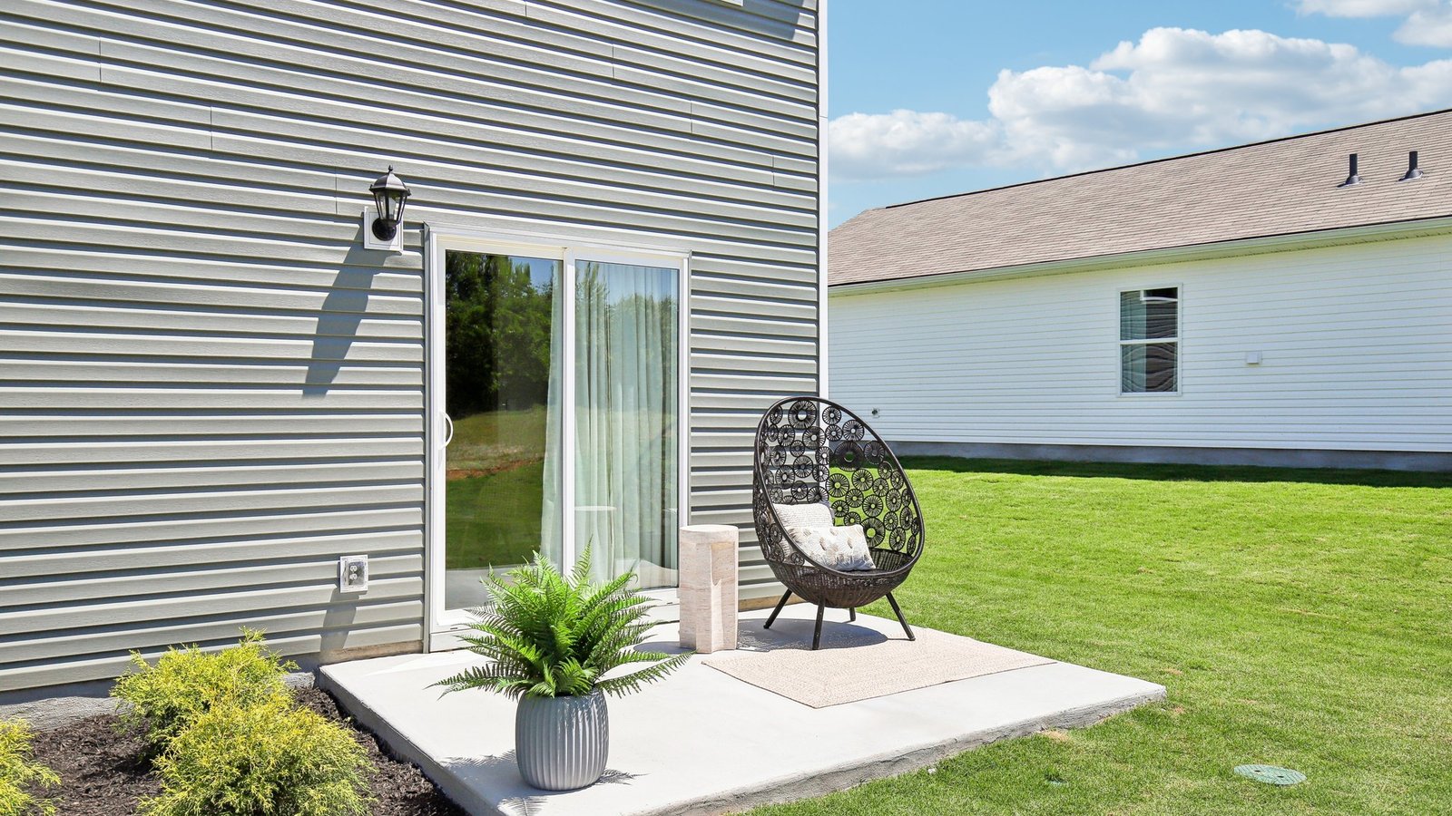 Backyard with concrete patio area offering room for seating, grill setup, and a transition from indoor to outdoor living