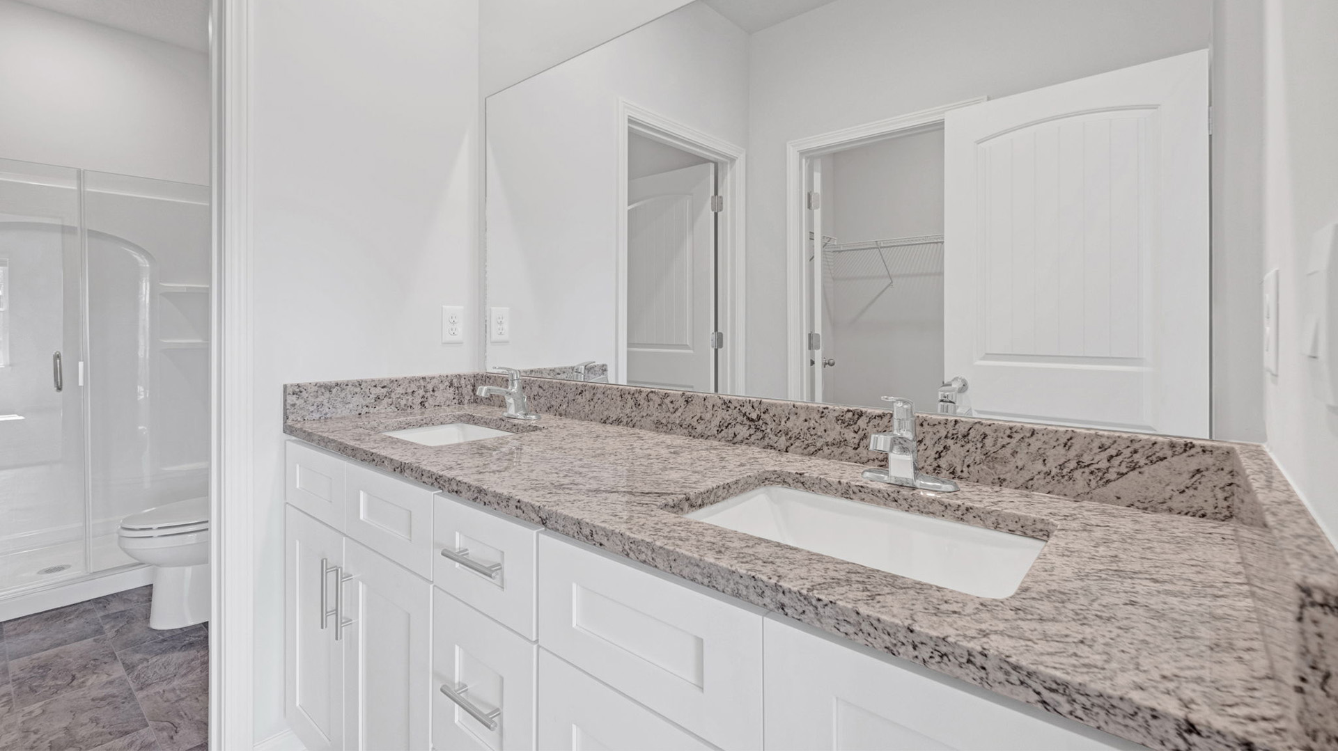 Ensuite primary bathroom with granite countertop vanity