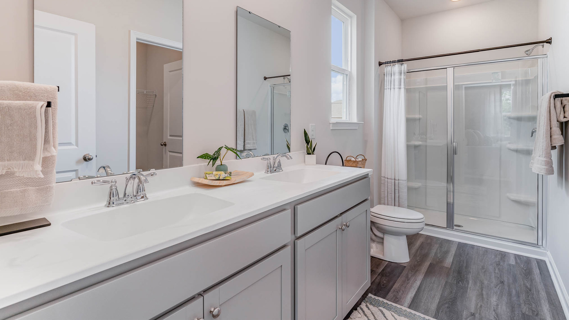en-suite primary bathroom with double vanity, two sinks, and glass enclosed walk-in shower