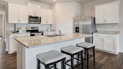 Beautiful kitchen area with light cabinets and stainless steel appliances